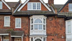 A traditional red brick house with a bay window and a front door.