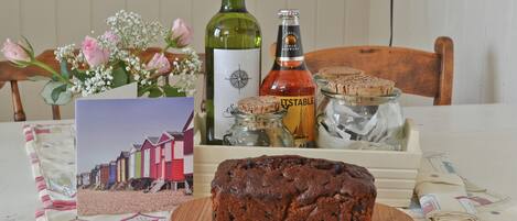 Une table avec un pain, une bouteille de vin, un bocal de biscuits, une carte et un vase de fleurs.