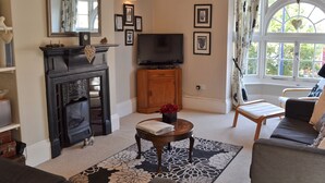 A living room with a fireplace, a television, and a window with curtains.
