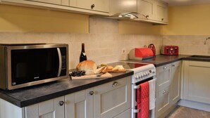 Une cuisine avec des armoires blanches, un four à micro-ondes en acier inoxydable, un grille-pain rouge et un four rouge.