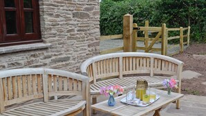 Deux bancs en bois, une table placée entre eux, un vase rempli de fleurs et un plateau avec des boissons et des verres.