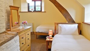 Une chambre à coucher avec un lit en bois, une commode, une table de chevet avec une lampe et une fenêtre donnant sur un paysage verdoyant.