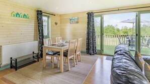 A cozy room with a wooden interior, a dining table with chairs, a sofa, and a view of the outdoors through a glass door. - 2 bedroom accommodation in Holsworthy, near Bude (Holsworthy, near Bude)