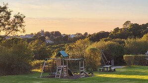 A grassy park with a wooden play structure and a picnic table. - 2 bedroom accommodation in Holsworthy, near Bude (Holsworthy, near Bude)