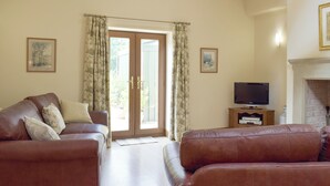 A living room with two brown leather sofas, a television on a wooden stand, and a fireplace. - Woodpecker Cottage - UKC3412 (Bolton-by-Bowland)