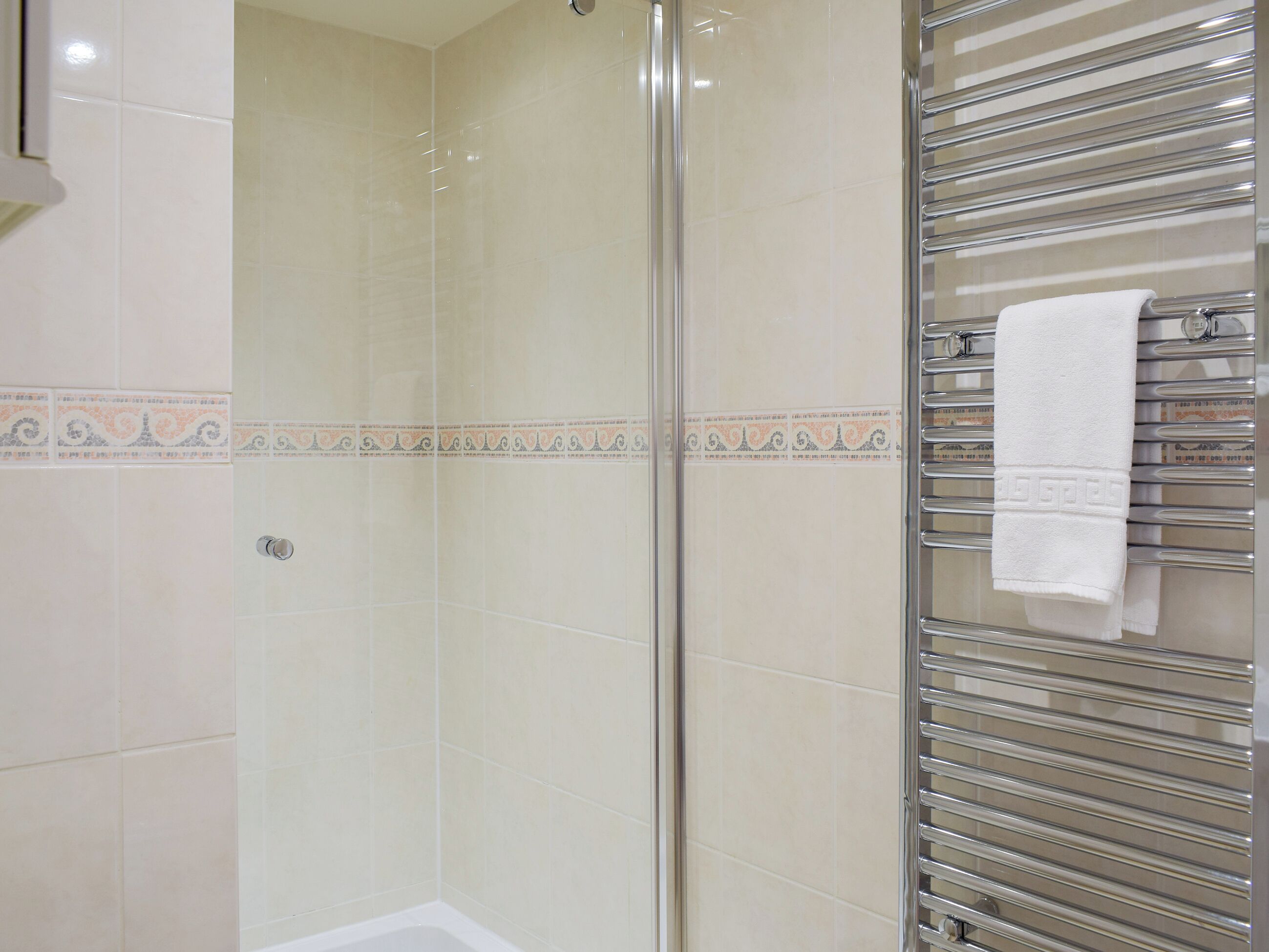 Une douche fermée par des parois en verre, avec un porte-serviettes en chrome.