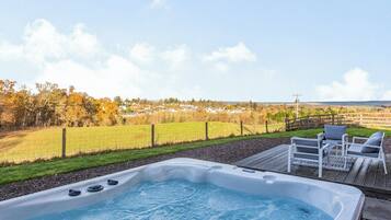 A hot tub with a view of a rural landscape, including fields and houses.
