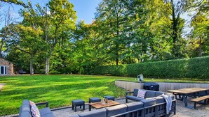 A backyard with a sectional sofa, a barbecue grill, and a wooden table. - 7 bedroom accommodation in North Duffield, near York (North Duffield, near York)