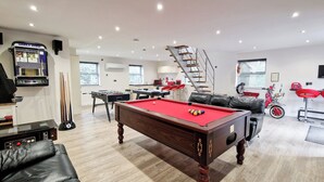 A spacious living room with a pool table, a foosball table, a sofa, a motorcycle, and a staircase. - 7 bedroom accommodation in North Duffield, near York (North Duffield, near York)