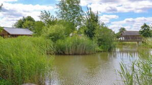 A riverside view with wooden buildings, dense greenery, and a wooden dock. - 2 bedroom accommodation in Thorpe on the Hill, near Lincoln (Thorpe on the Hill, near Lincoln)