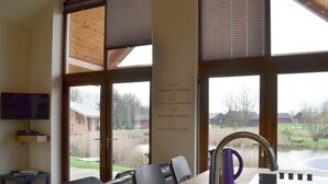 A kitchen with a wooden table, a sink, and a window with a view of a rural landscape. - 2 bedroom accommodation in Thorpe on the Hill, near Lincoln (Thorpe on the Hill, near Lincoln)