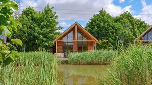 A wooden cabin with a large window, surrounded by tall grass and trees. - 2 bedroom accommodation in Thorpe on the Hill, near Lincoln (Thorpe on the Hill, near Lincoln)