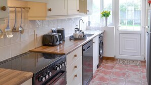 Een moderne keuken met een ingebouwde oven, een vaatwasser en een spoelbak. Er is een raam met uitzicht op groen.