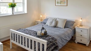 Een slaapkamer met een bed, nachtkastjes, een raam met uitzicht en een ingelijst kunstwerk aan de muur.