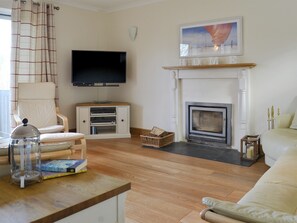 Ein Wohnzimmer mit Fernseher, Kamin und Sessel.
