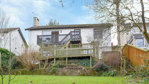A house with a wooden staircase leading to a balcony, surrounded by a garden with snowdrops. - 4 bedroom accommodation in Trusham, near Newton Abbot (Trusham, near Newton Abbot)