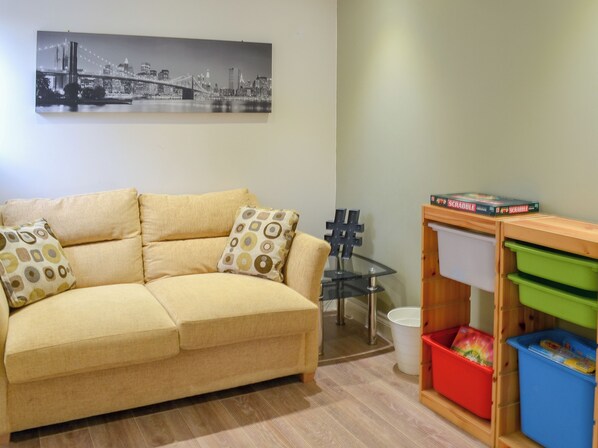 A living room with a sofa, a glass table, and storage units.