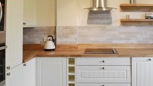 A kitchen with white cabinetry, a wooden countertop, a stainless steel range hood, and a tiled backsplash. - 4 bedroom accommodation in Trusham, near Newton Abbot (Trusham, near Newton Abbot)