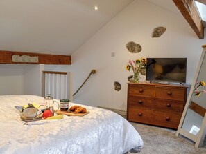 Un dormitorio con cama, cómoda, televisor y ventana con vistas al cielo.