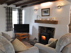 A cozy living room with a fireplace, a television, and comfortable seating. - 1 bedroom accommodation in Penysarn (Penysarn)