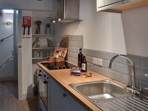 A modern kitchen with a wooden countertop, stainless steel sink, and a built-in oven. - 1 bedroom accommodation in Penysarn (Penysarn)
