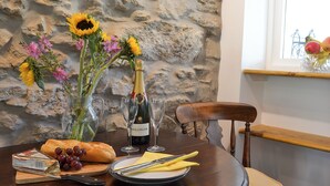 Et spisebord med en flaske Bollinger champagne, et brød, druer og en blomstbuket.