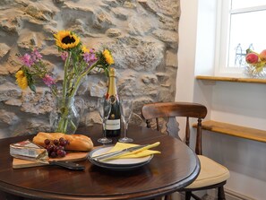 A dining table with a bottle of Bollinger champagne, a loaf of bread, grapes, and a bouquet of flowers.