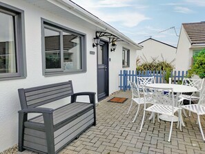 A patio with a bench and white outdoor furniture. - 2 bedroom accommodation in St Merryn, near Padstow (St Merryn, near Padstow)