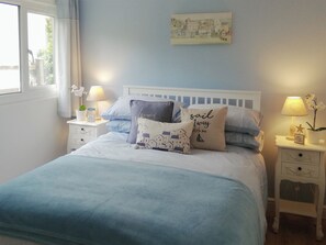 A neatly made bed with a blue blanket, two bedside tables with lamps, and decorative pillows. - 2 bedroom accommodation in St Merryn, near Padstow (St Merryn, near Padstow)