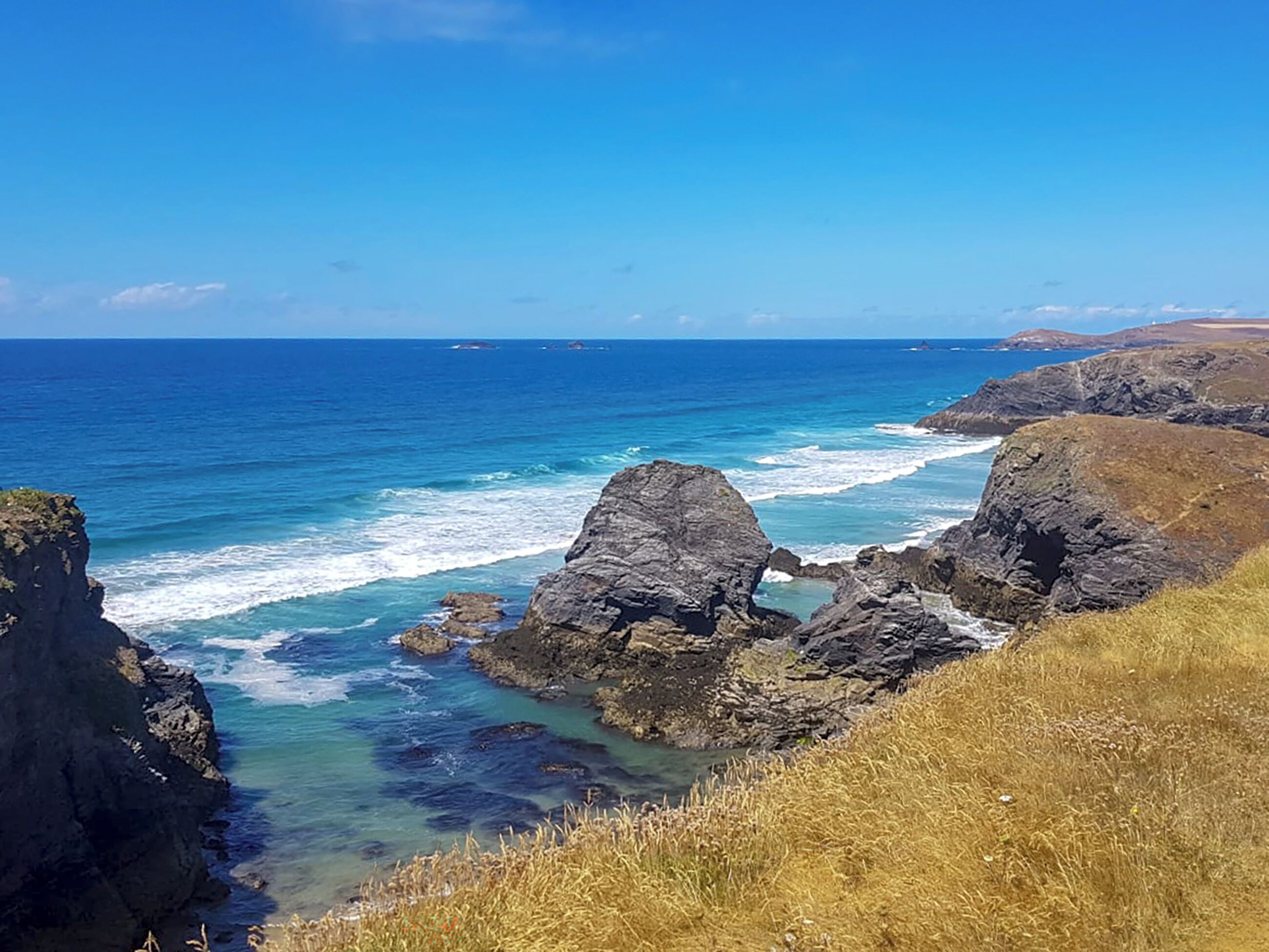A coastal landscape with rocky cliffs and clear blue sea.