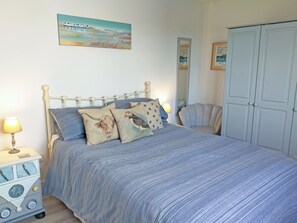 A bedroom with a bed, a nightstand, a chair, and a wardrobe. - 2 bedroom accommodation in St Merryn, near Padstow (St Merryn, near Padstow)