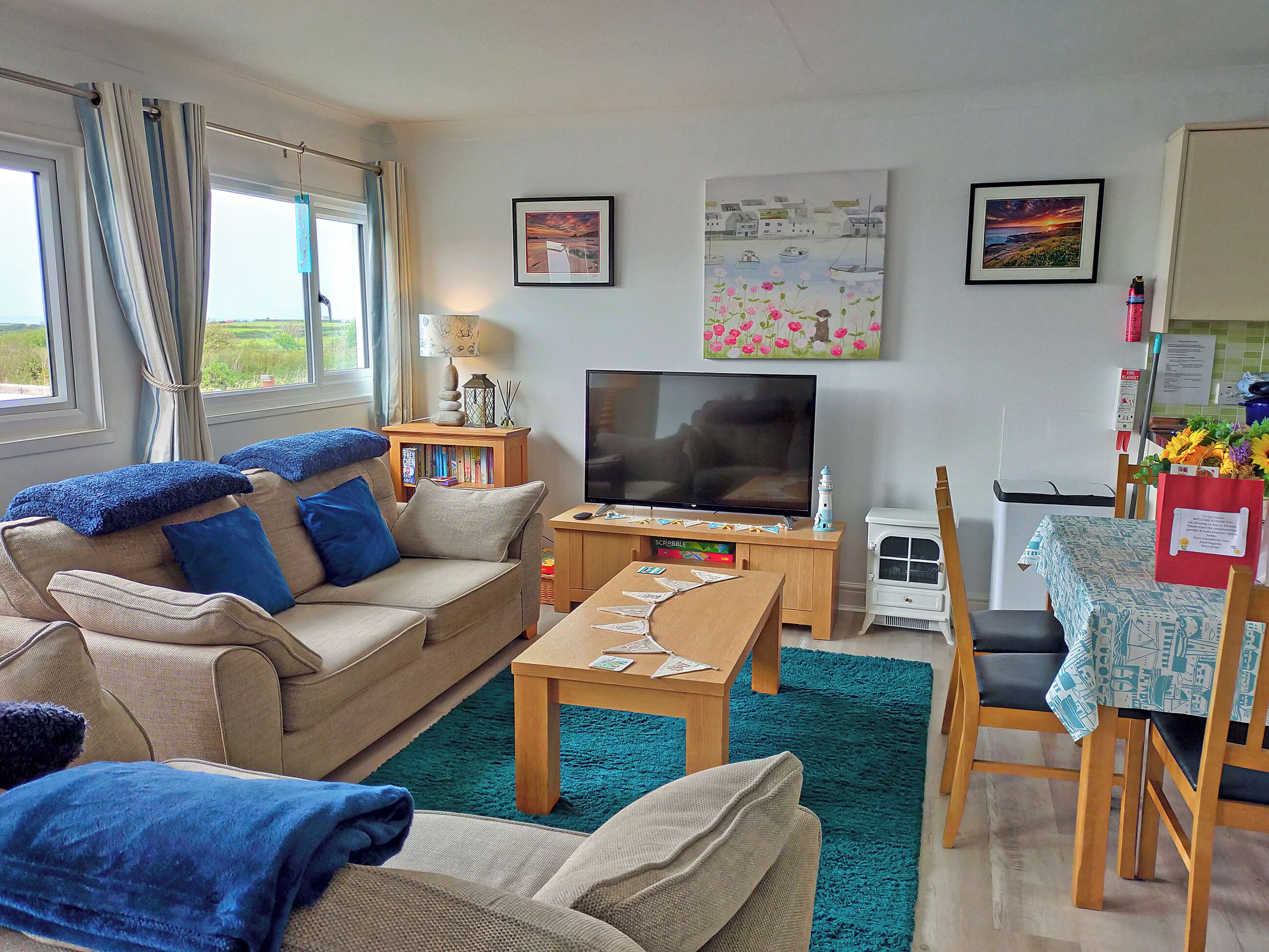 A living room with a sofa, a coffee table, a TV, and a small table with a lamp and books.