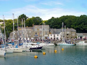 A marina with several boats docked, surrounded by buildings with shops and galleries.