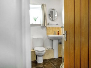 A bathroom with a toilet, sink, and mirror.