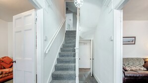 Una escalera con barandilla, escalones alfombrados y paredes blancas.