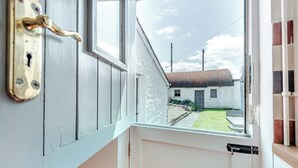 Una habitación con ventana, una puerta con cerradura y vista a un edificio.
