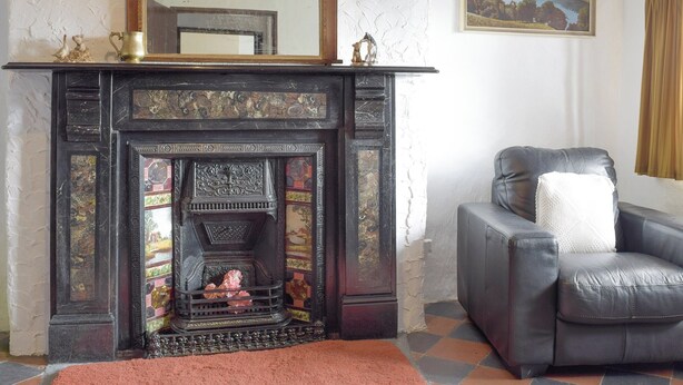 A room with a fireplace, a leather armchair, and a painting on the wall. - 3 bedroom accommodation in Cynheidre, near Llanelli (Cynheidre, near Llanelli)