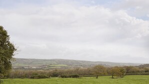 A rural landscape with rolling hills, a grassy field, and a distant village. - 3 bedroom accommodation in Cynheidre, near Llanelli (Cynheidre, near Llanelli)
