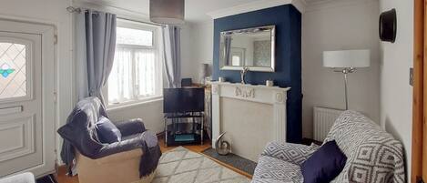 Ein Wohnzimmer mit Kamin, Fernseher und einer Couch.