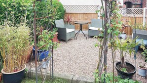 Un patio con mobiliario exterior, cerca de madera y plantas en macetas.