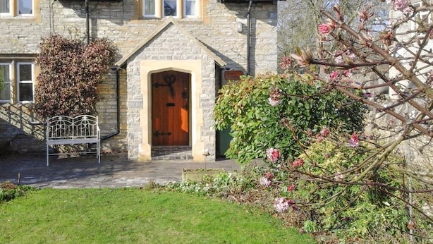 A stone house with a wooden door, a bench, and blooming flowers in the garden. - Enchanting 17th Century Cotswold Cottage in the beautiful village of Bretforton  (Bretforton, Evesham)