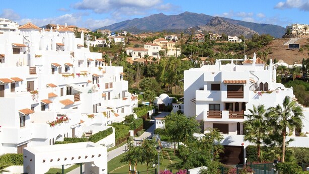 A coastal town with white buildings, a mountain in the background, and a clear sky. - Golf Hills Marbella - Beautiful decorated incl. lounge terrace (Estepona)