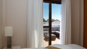 A hotel room with a bed, a bedside lamp, and a view of a balcony with outdoor furniture. - Golf Hills Marbella - Beautiful decorated incl. lounge terrace (Estepona)