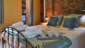 A neatly made bed with pillows, a tray with cups and a teapot, and a view of a stone wall and a door leading to a bathroom. - 2 bedroom accommodation in Dwyran, near Llanfairpwllgwyngyll (Dwyran, near Llanfairpwllgwyngyll)