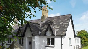 A white cottage with a steeply pitched roof, a chimney, and a stone sign reading "TRE ANNA". - 2 bedroom accommodation in Dwyran, near Llanfairpwllgwyngyll (Dwyran, near Llanfairpwllgwyngyll)
