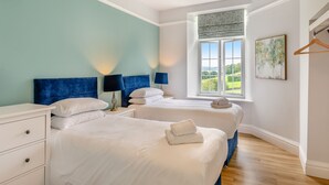 Ein Hotelzimmer mit zwei Betten, einem Fenster mit Blick, einer Hängelampe und einem Bild an der Wand.