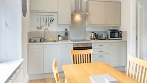 Eine moderne Küche mit weißen Schränken, einer Edelstahl-Spüle, einem Toaster, einem Wasserkocher und einer Mikrowelle.