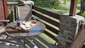 Une table à plateau en verre, sur laquelle se trouve un plateau de nourriture, des chaises en osier et un mur en pierre.