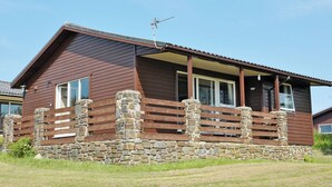 Une cabane en bois avec des fondations en pierre, de grandes fenêtres et un toit en pente.