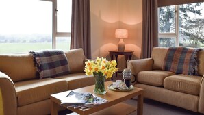 A cozy living room with two sofas, a coffee table, a lamp, and a vase of flowers. - 3 bedroom accommodation in near Chipping Warden (near Chipping Warden)